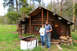 1989 Ford Bronco - A couple poses for a photo outside a wooden cabin, with an old stove in front of them.