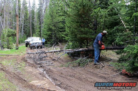 1989 Ford Bronco on muddy road, man cutting tree