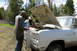 1989 Ford Bronco - Two men attend to the engine of a white pickup truck in a wooded area.