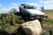 1989 Ford Bronco - A Ford F-Series truck navigates a challenging off-road terrain, with a second vehicle attached by a tow rope.