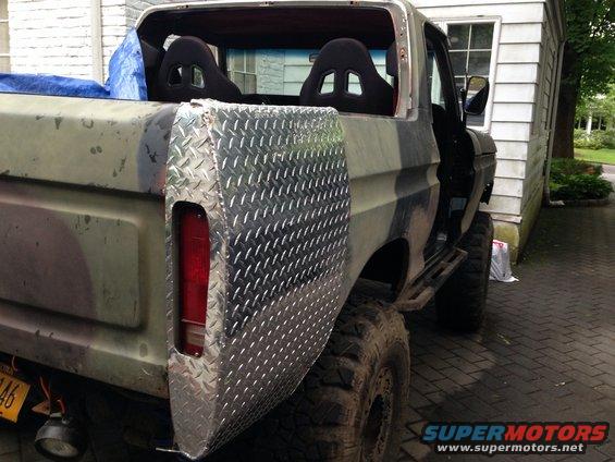 Camouflaged Ford Bronco with diamond plate rear panel and racing seats, viewed from the rear