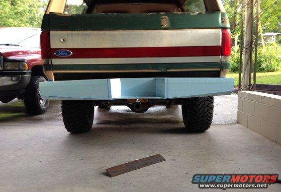 Green and white Ford Bronco with red stripe, light blue custom bumper, rear view