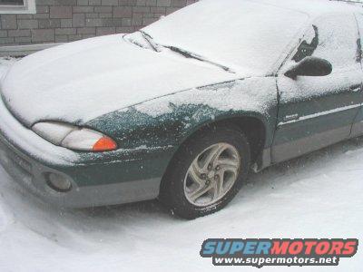Green sedan parked outside in the snow. The car is partially covered in snow