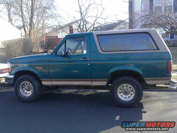 Side view of a green 1996 Ford Bronco with a tan top