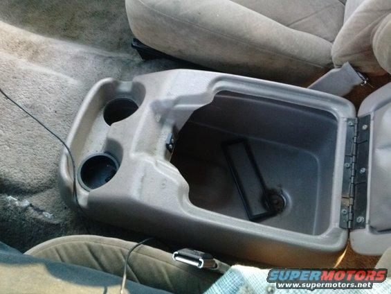 Tan fabric seats and gray plastic center console with open storage compartment and cup holders