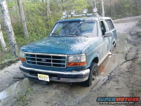 Teal 1996 Ford Bronco stuck in mud, front view