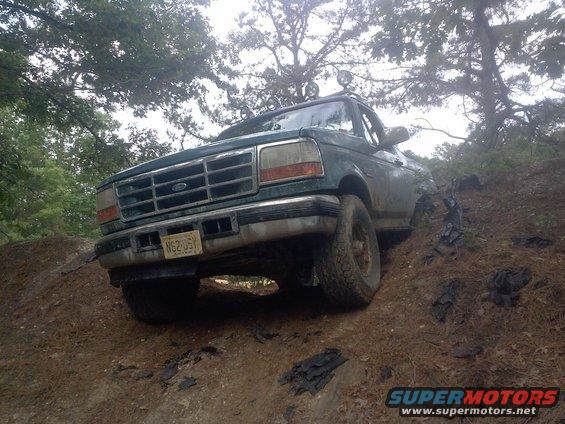 Green 1996 Ford Bronco driving off-road on a dirt hill