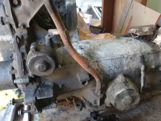 close-up of dirty engine block and transmission with a rusty pipe running over it