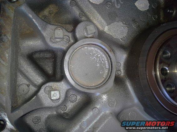 Close-up of an engine block with a circular plug and some bolts visible
