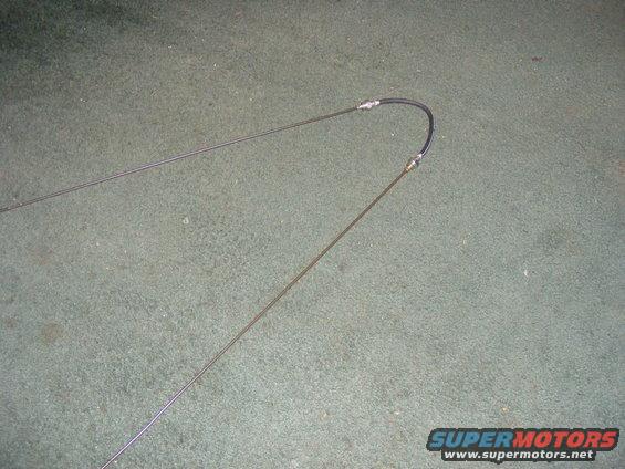 Two throttle cables, one with a black protective sleeve, laid out on a carpeted surface