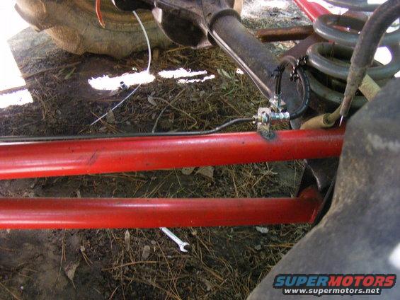 Close-up of red suspension bars, brake lines, and a tire on a vehicle