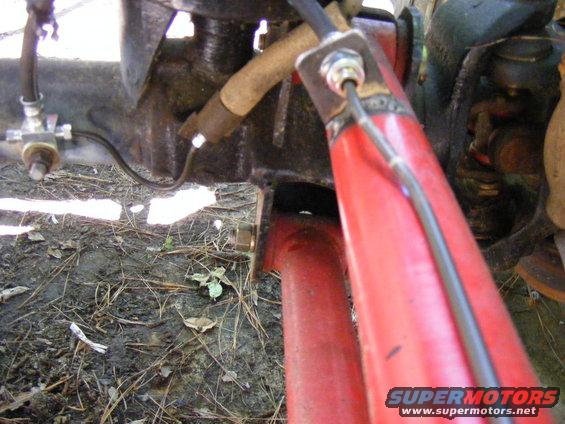 Close-up of red suspension part and brake line attached to black metal