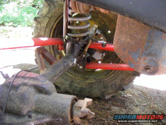 Close-up of a vehicle's rusty axle and red suspension components