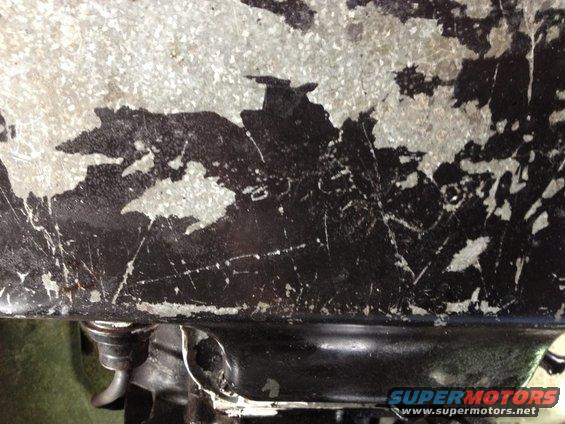 Close-up of a weathered metal surface with peeling black and silver paint