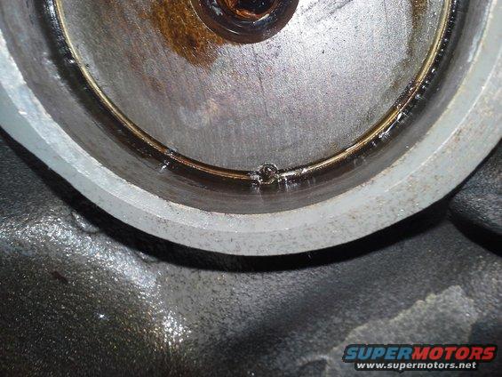 Close-up of a metal engine part with oil residue and a small bubble