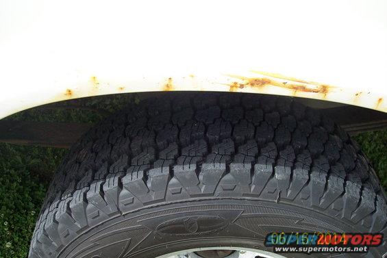 White vehicle fender with rust above a tire. Visible text: 06/16/2004 SUPERMOTORS.NET