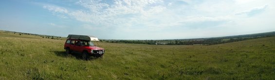 Red SUV parked in grassy field, canoe on roof rack