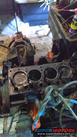 Engine block with cylinders exposed, showing internal components and wiring. A can of WD-40 is visible in the background