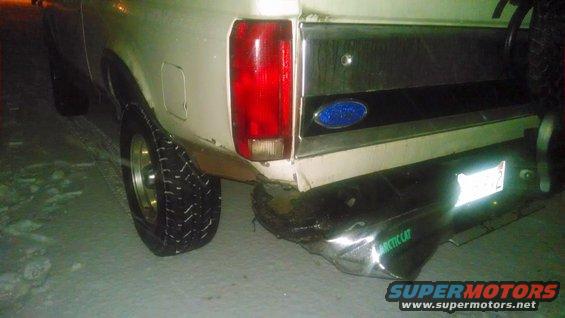 Rear view of a white Ford Bronco with a chrome bumper and a blue Ford oval emblem. The vehicle is on a snowy surface
