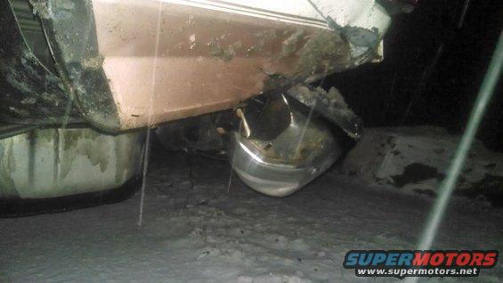 Damaged rear bumper and lower body panel of a vehicle, possibly a truck or SUV, in a snowy outdoor setting
