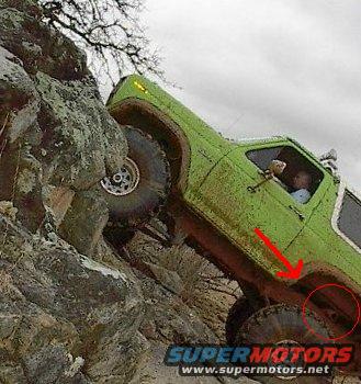 Green off-road vehicle with large tires climbing a steep, rocky slope