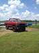 1978 Ford Bronco - A red 1978 Ford Bronco sits on a grassy area next to a body of water under a cloudy sky.
