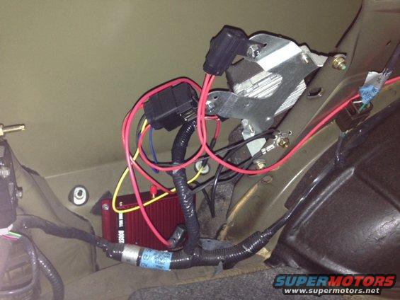 Aftermarket electronic boost controller wiring with red and yellow wires, fuse box, and metal bracket