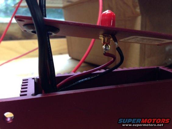 close-up of red electronic box with wires connected to a circuit board and a red antenna-like object