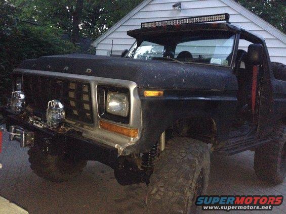 Front end of a black Ford Bronco with a custom grille and light bar. It has aftermarket lights and large tires