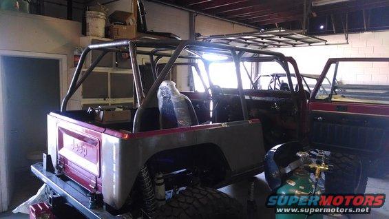 Jeep CJ body with roll cage, unfinished, maroon rear panel, in workshop