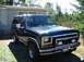 1983 Ford Bronco - This black Ford Bronco is parked in front of a trailer on a sunny day.