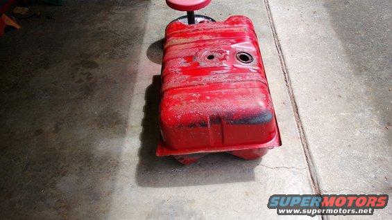 Red fuel tank resting on a red stool on a concrete floor