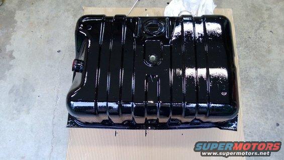 black fuel tank, possibly for a truck or SUV, sitting on cardboard