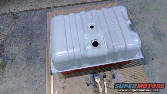 White fuel tank with red underside, sitting on cardboard with paintbrushes