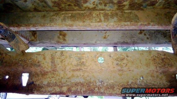 Underside of a vehicle frame with significant rust