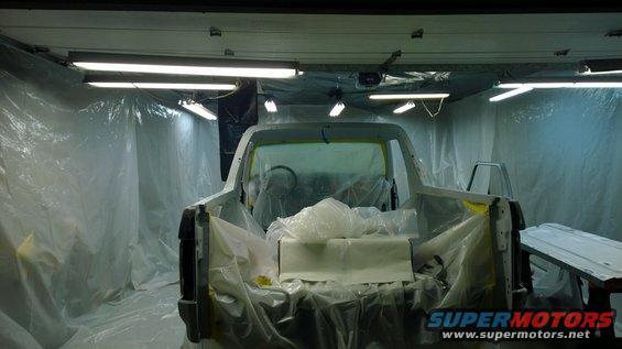 1983 Ford Bronco in a paint booth, covered in plastic, rear view