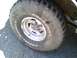1979 Ford Bronco - Close-up of a Mudder Buckshot radial tire mounted on a silver five-spoke rim.