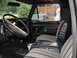 1979 Ford Bronco - The interior of a truck shows a worn steering wheel, patterned seats, and a floor shifter.