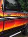 1979 Ford Bronco - Side view of a black 1978 Ford Bronco with a distinctive flame-like stripe and visible damage.