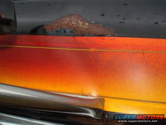 Rusty vehicle side panel with orange and red gradient decal and chrome trim