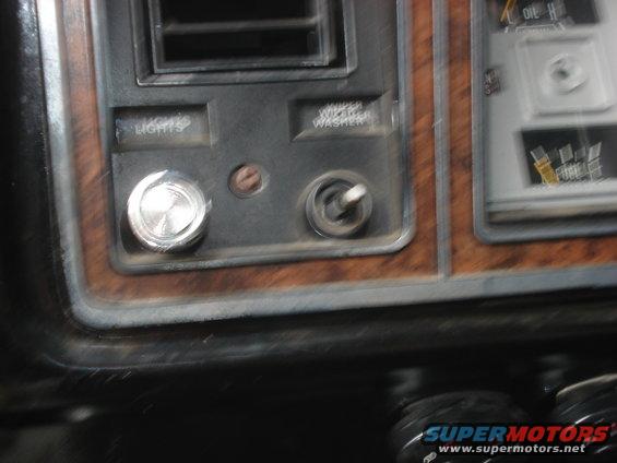 Dashboard with woodgrain trim, a toggle switch, a rotary knob labeled LIGHTS, and part of a gauge cluster