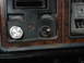 1979 Ford Bronco - Close-up of a vehicle's interior dashboard, wood grain trim and control buttons for lights and wipers.