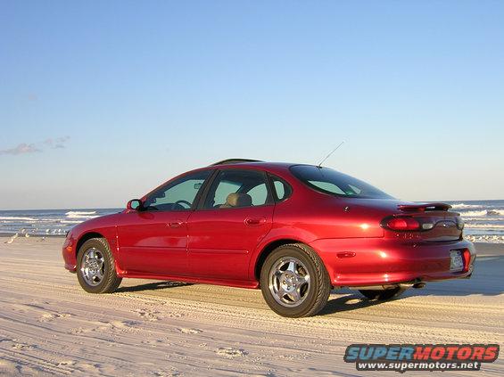 1997 Ford Taurus SHO parked on a sandy beach with the ocean in the background