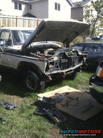 Two-tone 1979 Ford Bronco with hood open, front grille removed, parked on grass