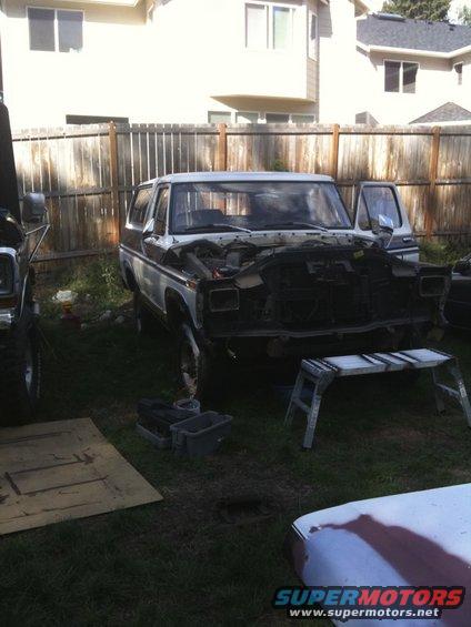 Ford Bronco with hood open, parked in a yard with another vehicle partially visible