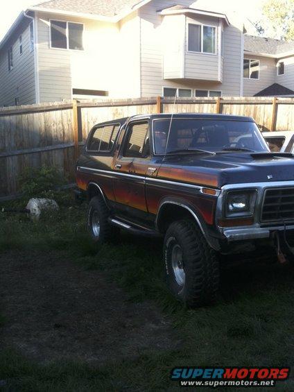 Dark blue and orange striped 1978 Ford Bronco with aftermarket wheels parked on grass