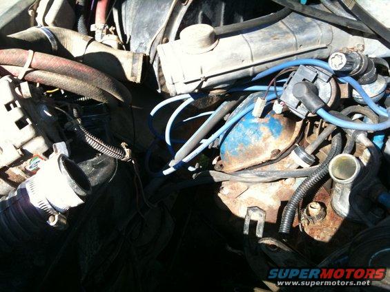 Engine bay with hoses, wires, and engine components visible
