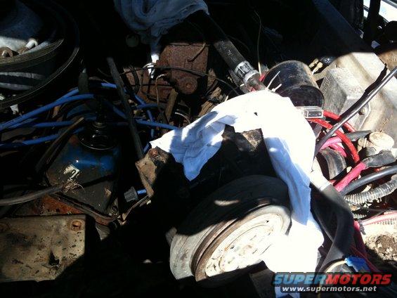 Engine bay with blue hoses, rusty components, and white cloth covering parts. A "SUPERMOTORS" watermark is visible