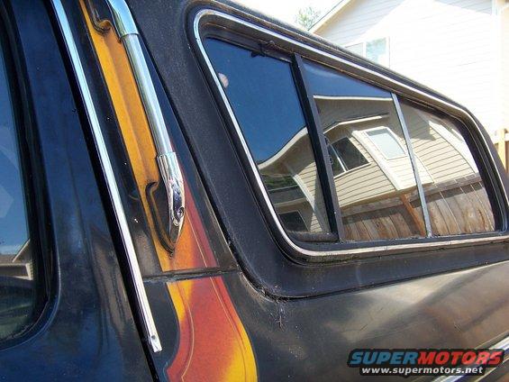 Black 1979 Ford Bronco side window with chrome trim and flame decal detail