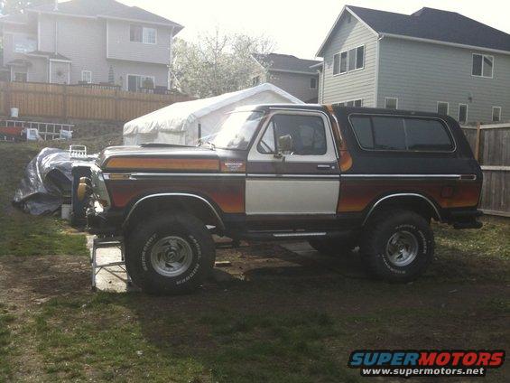 Brown and white Ford Bronco with orange accents, lifted, on grass